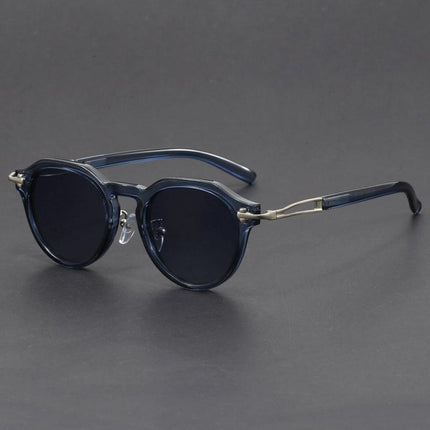 Anteojos de sol vintage negros con lentes oscuros, forma redonda y detalles metálicos; sofisticados para adultos.