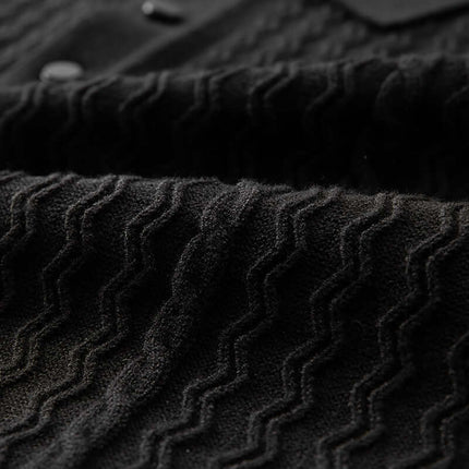 Detalle de chomba Torino negra con patrón texturizado de ondas, ideal para hombre, tejido transpirable y corte slim.