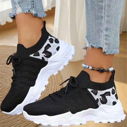 Zapatillas Mujer WildFit negras, tejido knit elástico, suela deportiva blanca, detalle animal print, estilo moderno.