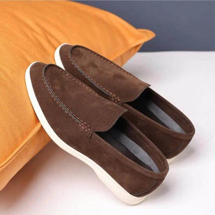 Zapatos informales sin cordones de gamuza marrón para hombre, diseño cómodo sobre fondo naranja.