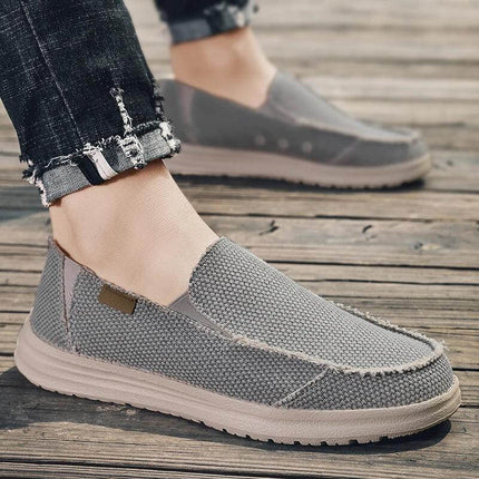 Zapatos informales transpirables de lona gris para hombre sobre un fondo de madera, estilo cómodo y casual.